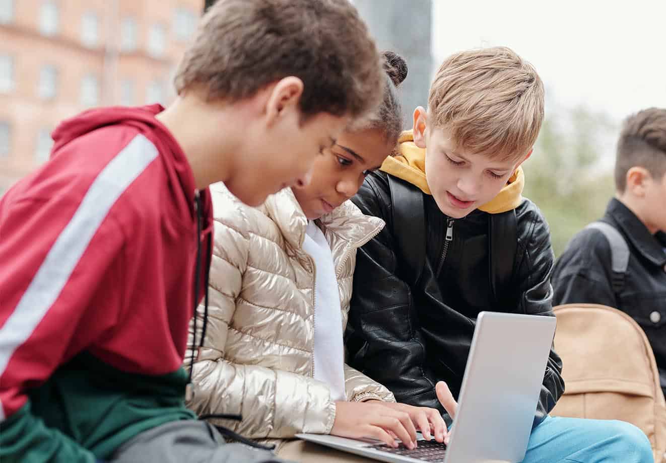 Three students working on a laptop.
