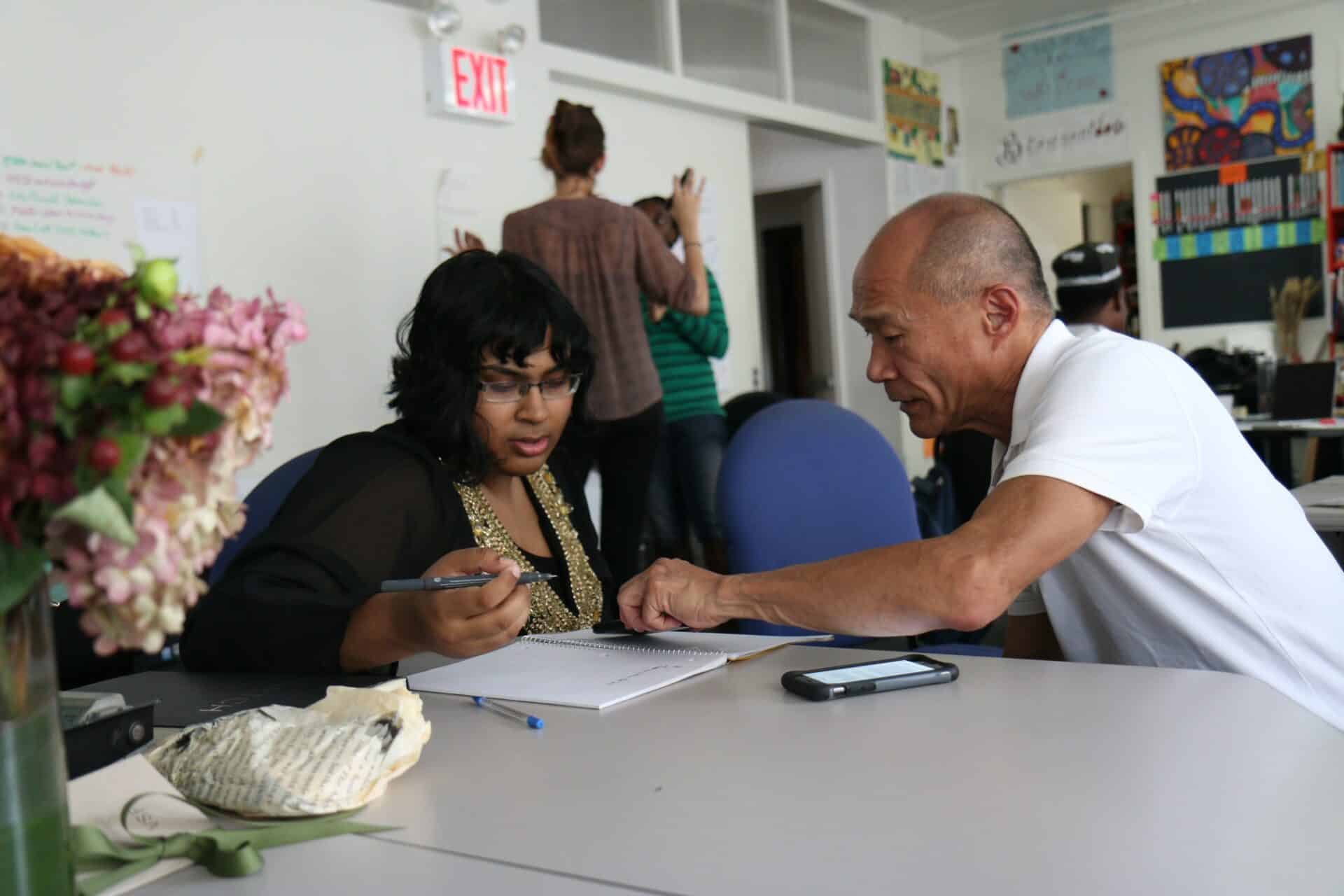 Two coworkers sit at a table and engage in soft skills