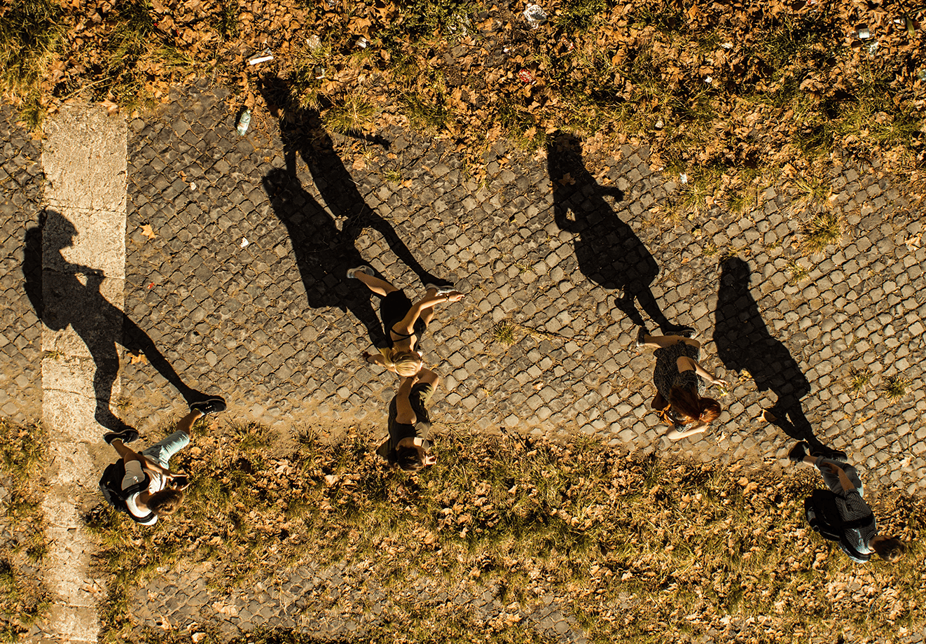 Students with dark shadows walking down a path.