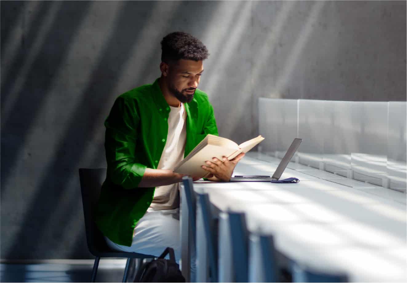 Man reading at a table with a laptop