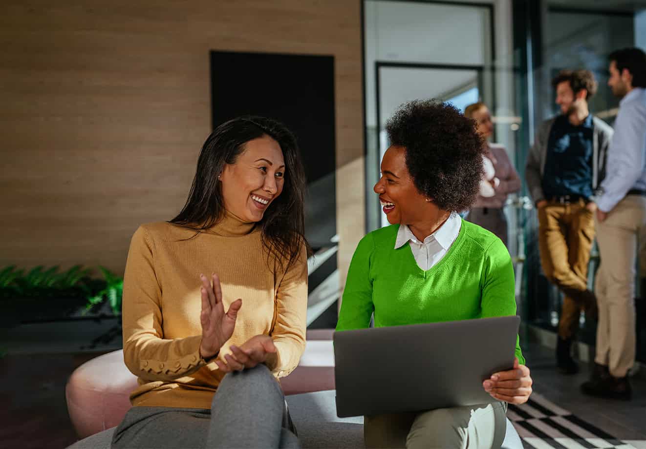 Two people happily working on a laptop