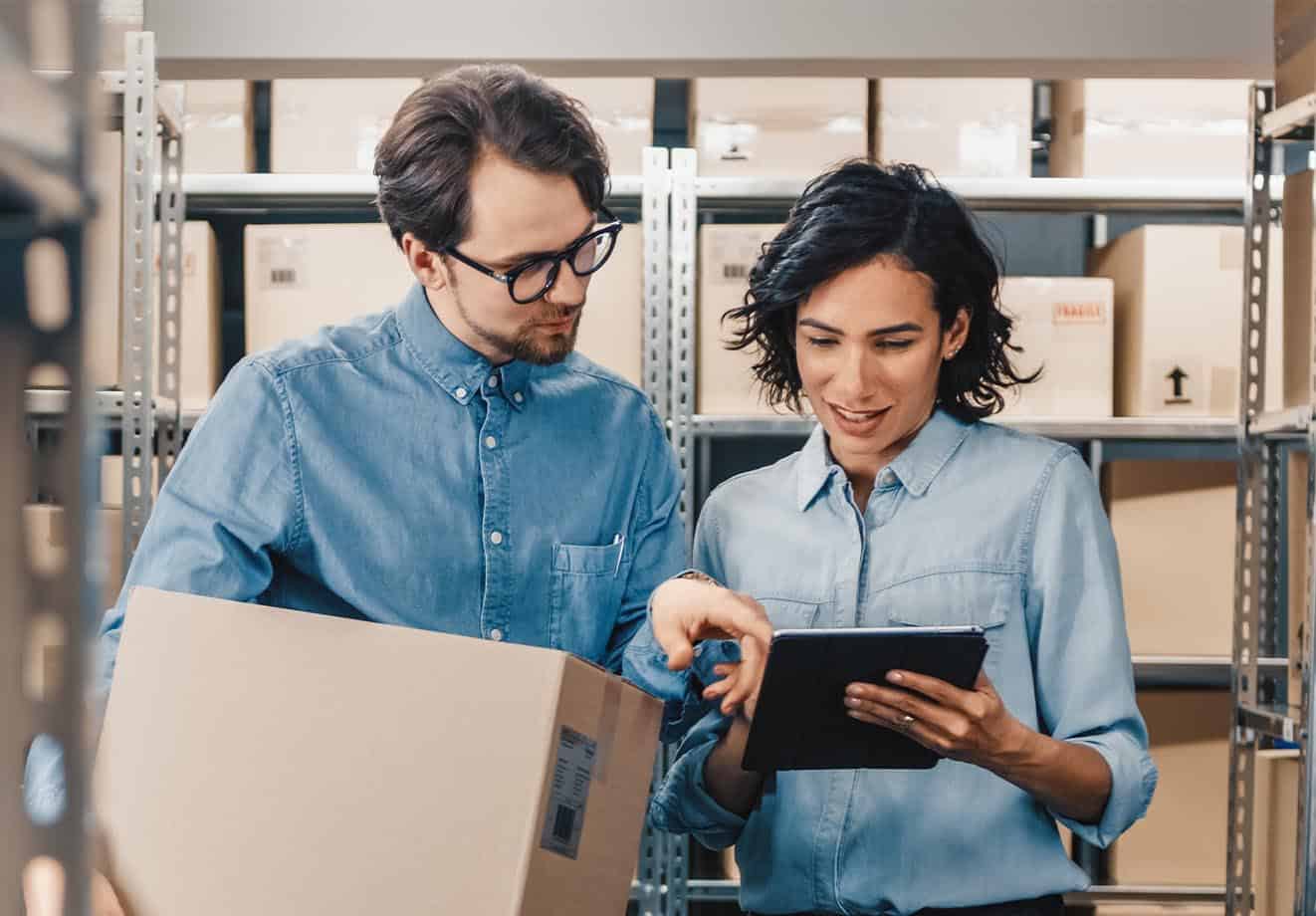 Two workers looking at a tablet in a warehouse.