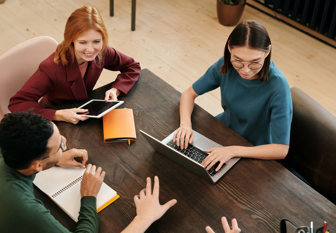 Three people working at a desk on laptops
