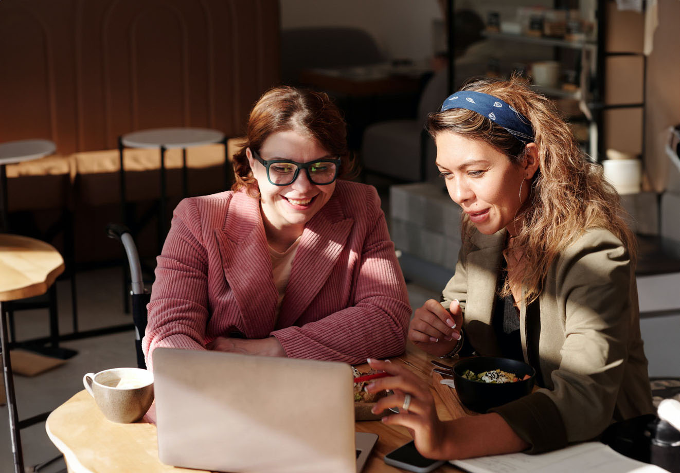 Two coworkers collaborating at a table behind a laptop