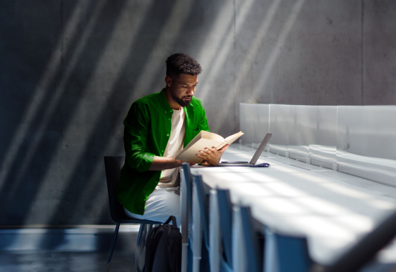 Man reading at a table with a laptop in front of him