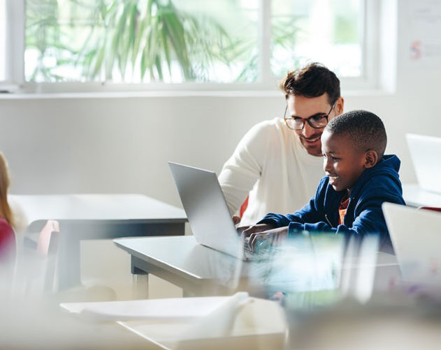 Teacher helping student on laptop