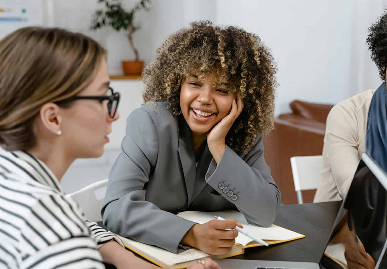 Coworkers collaborating at a work table with an open laptop