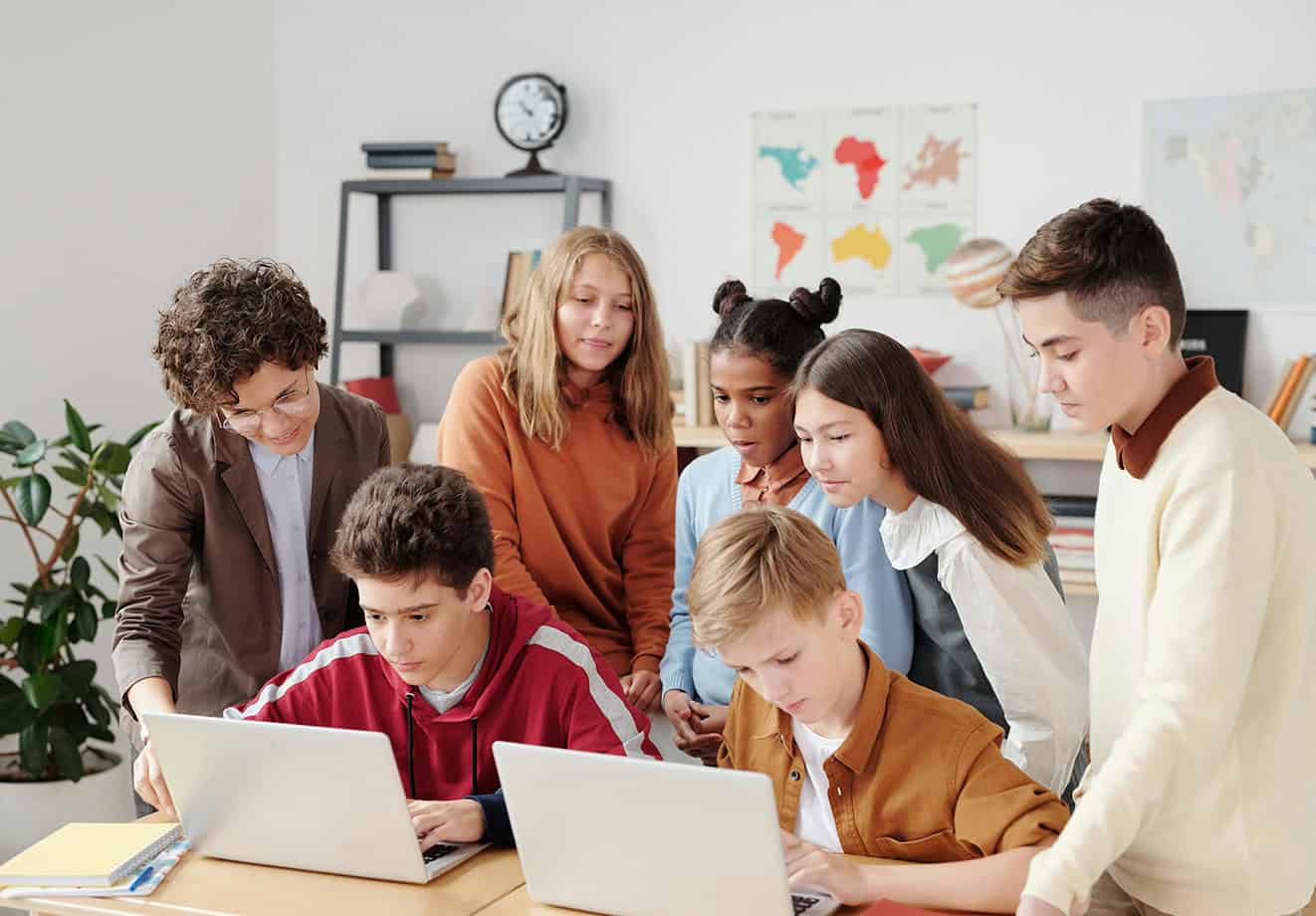 Students gathered around two computers in a classroom