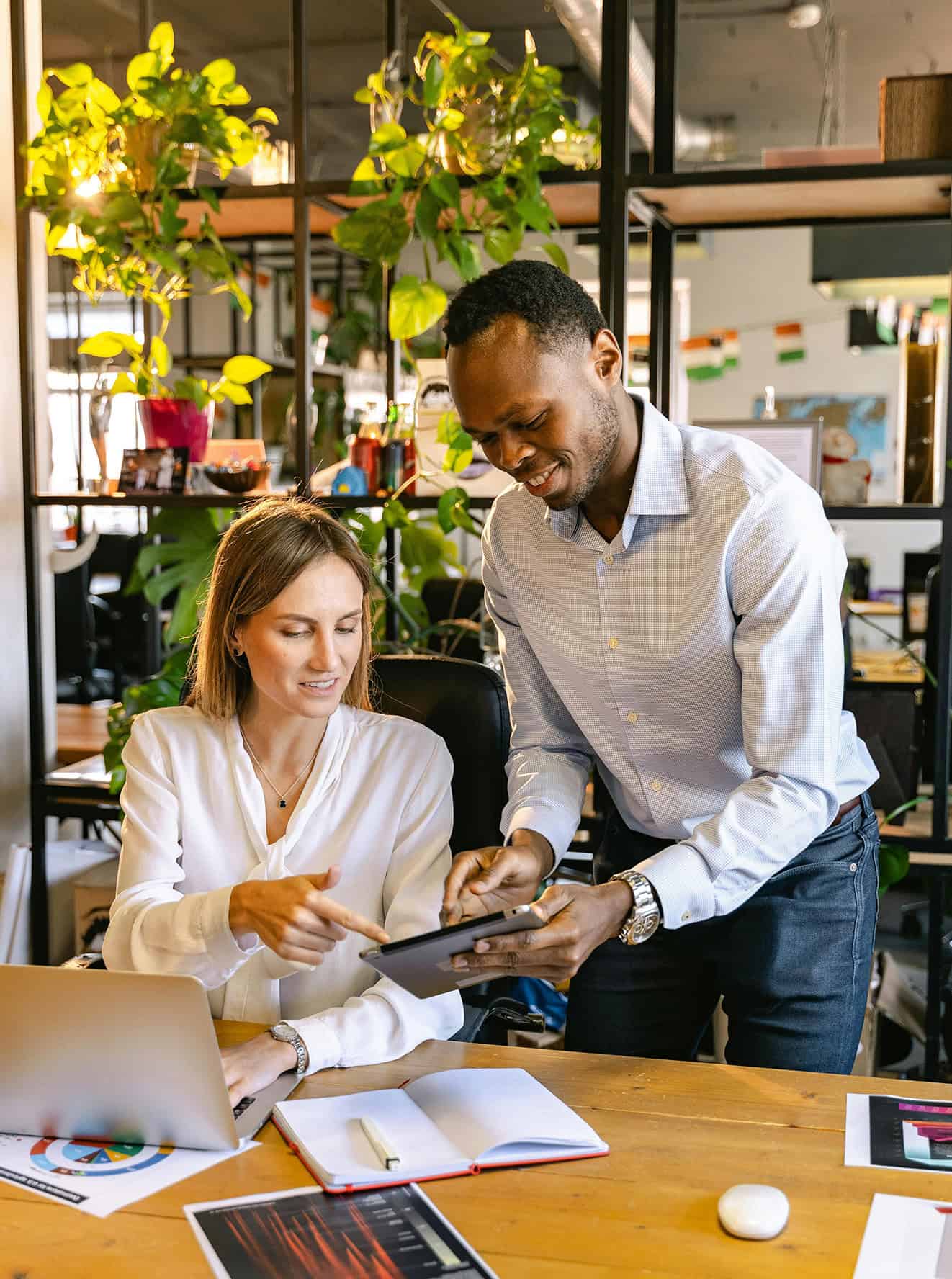 two coworkers collaborating over a desk with a tablet