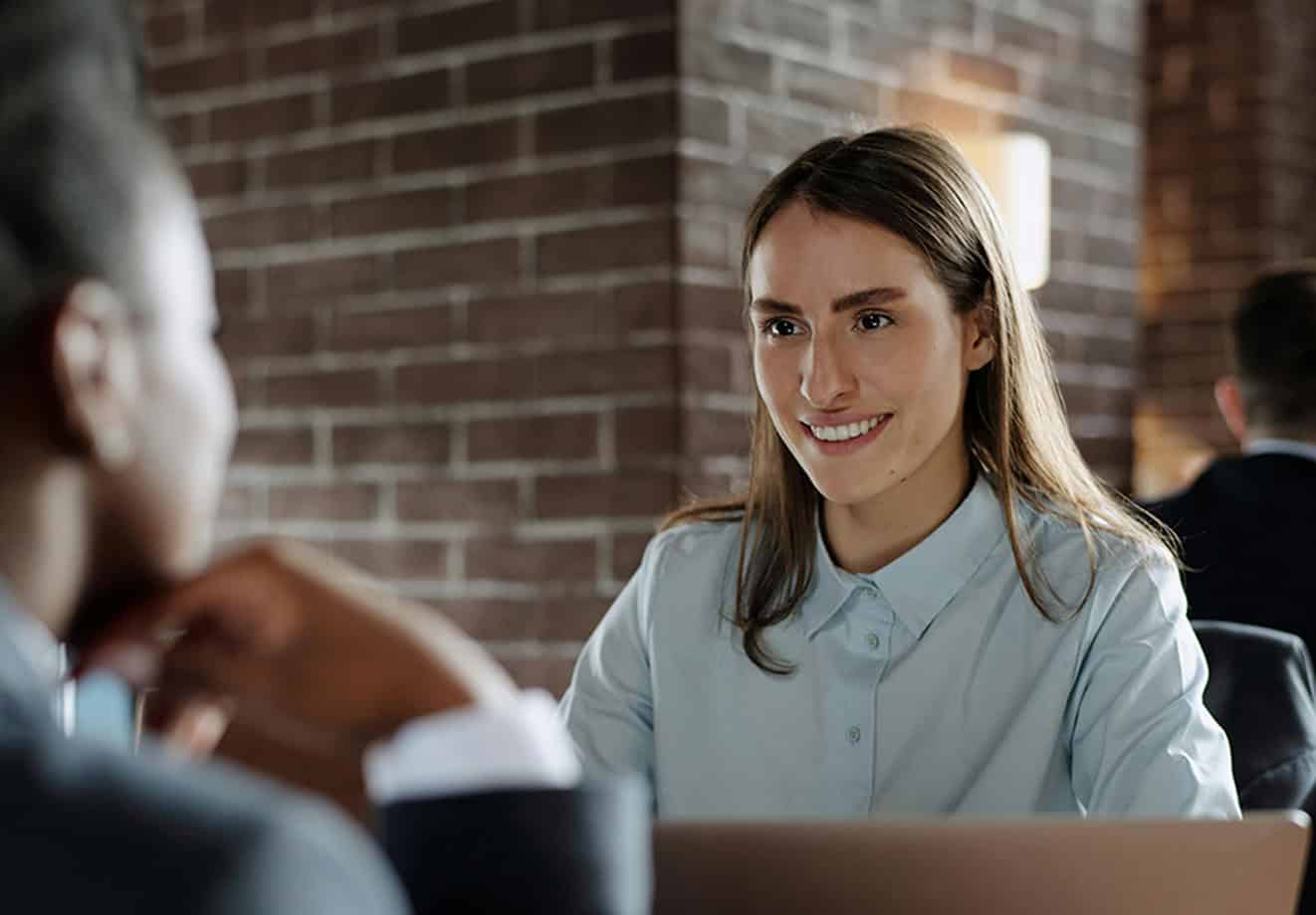 Two women talking at table with open laptop
