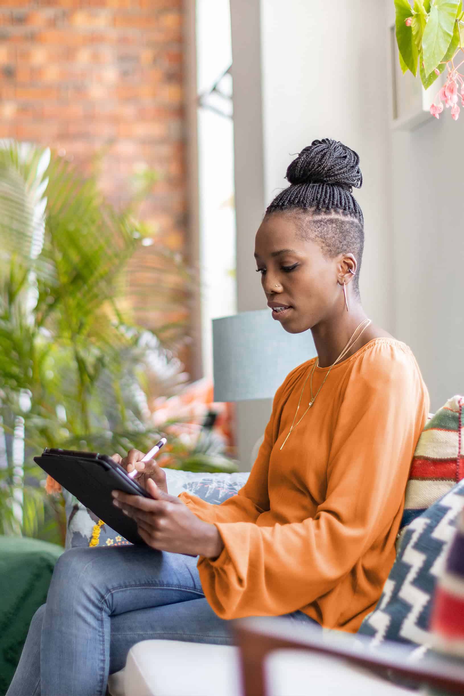Woman sitting on couch working on tablet