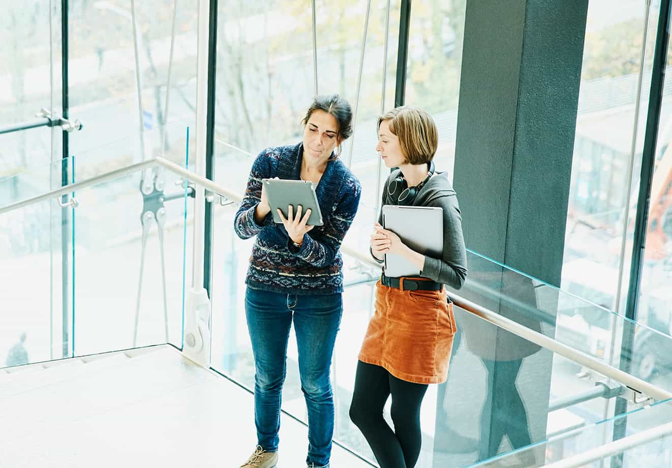 Two colleagues collaborating over a tablet