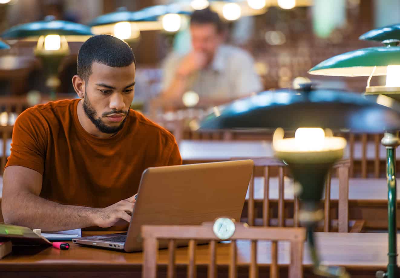 University student typing on laptop at outdoor table