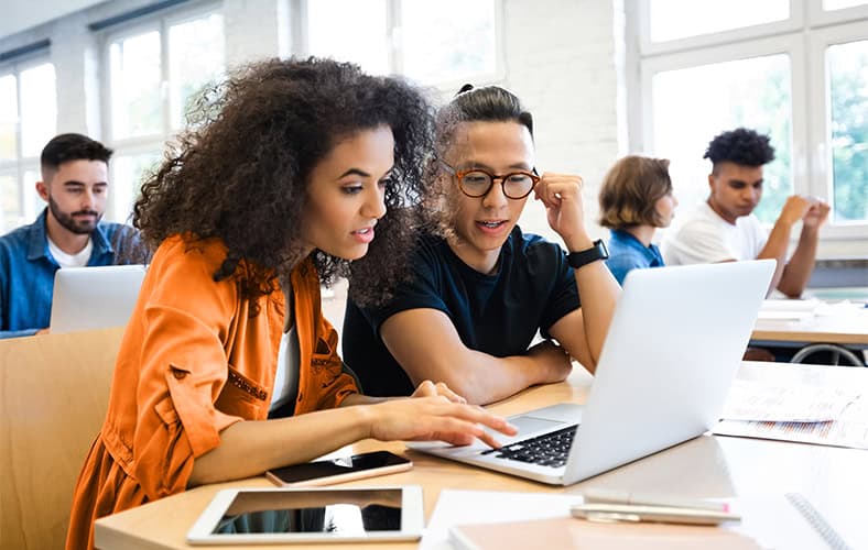 two professionals collaborating at a table with a laptop