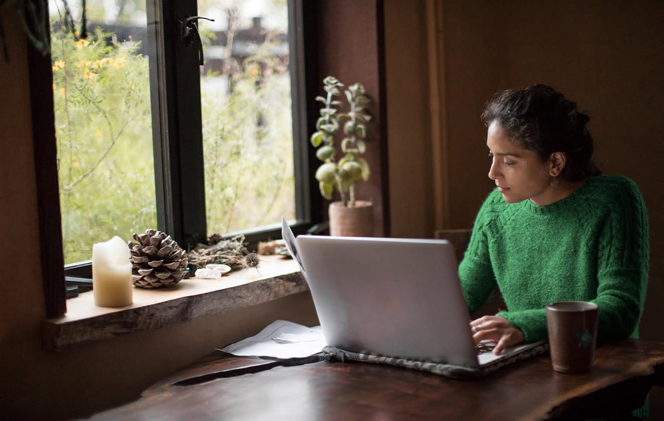 Woman working on laptop near window