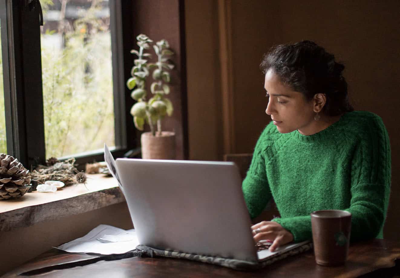 Woman working on laptop near window