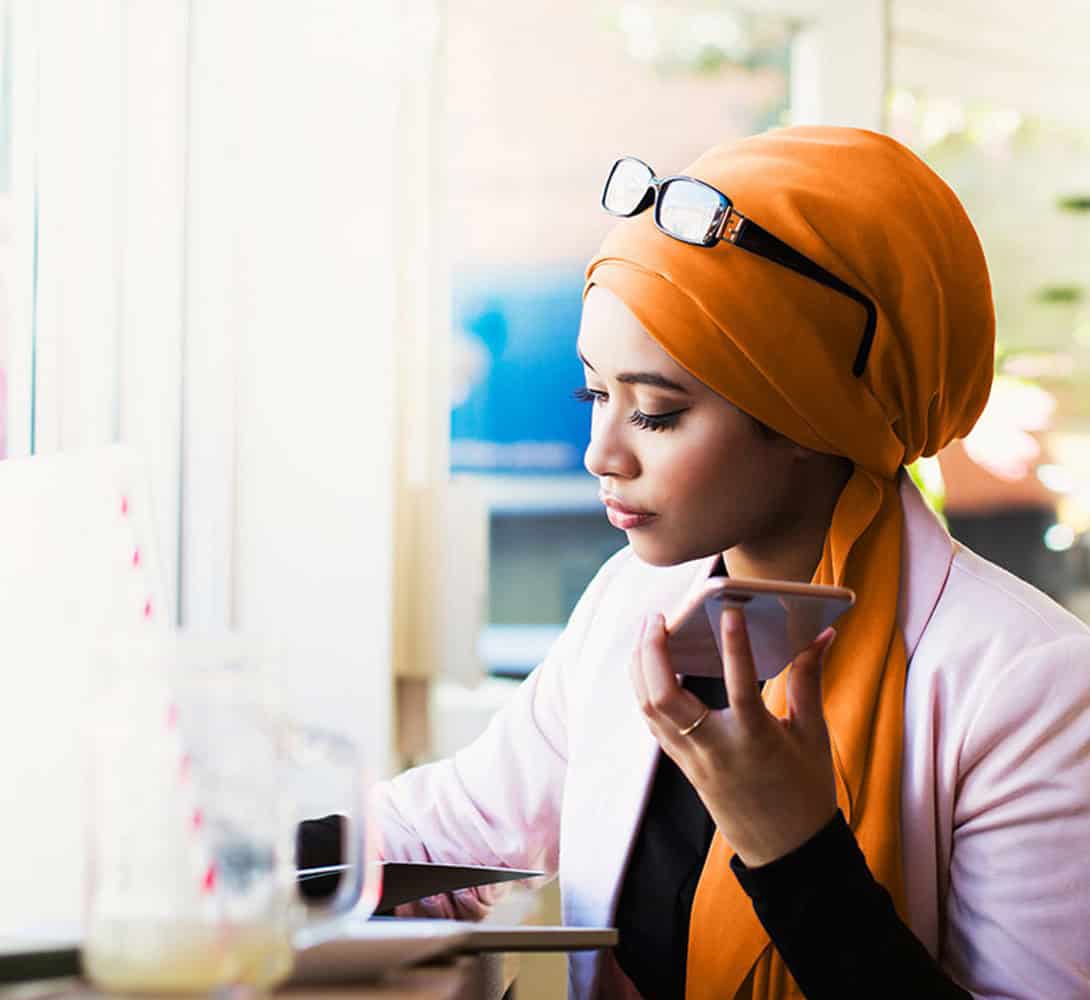 Woman speaking on phone while writing notes at desk