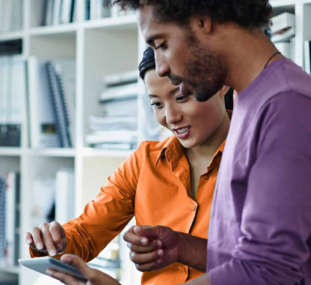 Two colleagues talking while holding tablet