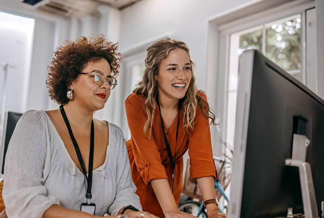 Two business colleagues working together on desktop computer at office