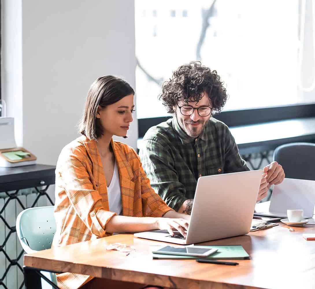 Two colleagues working at desk together with laptop