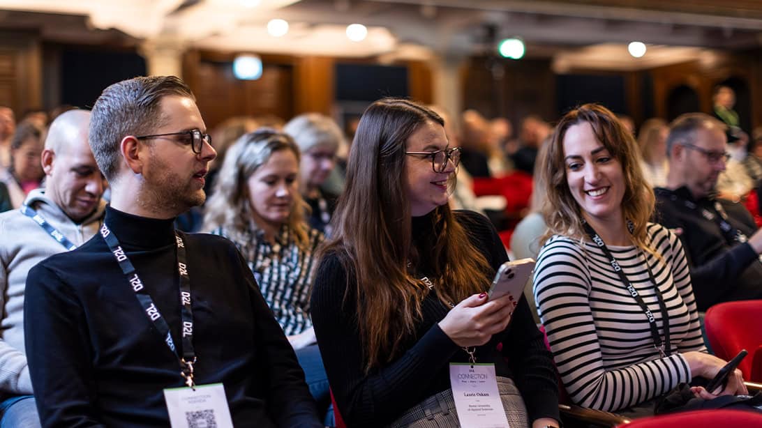 Three professionals sitting in lecture hall during business event
