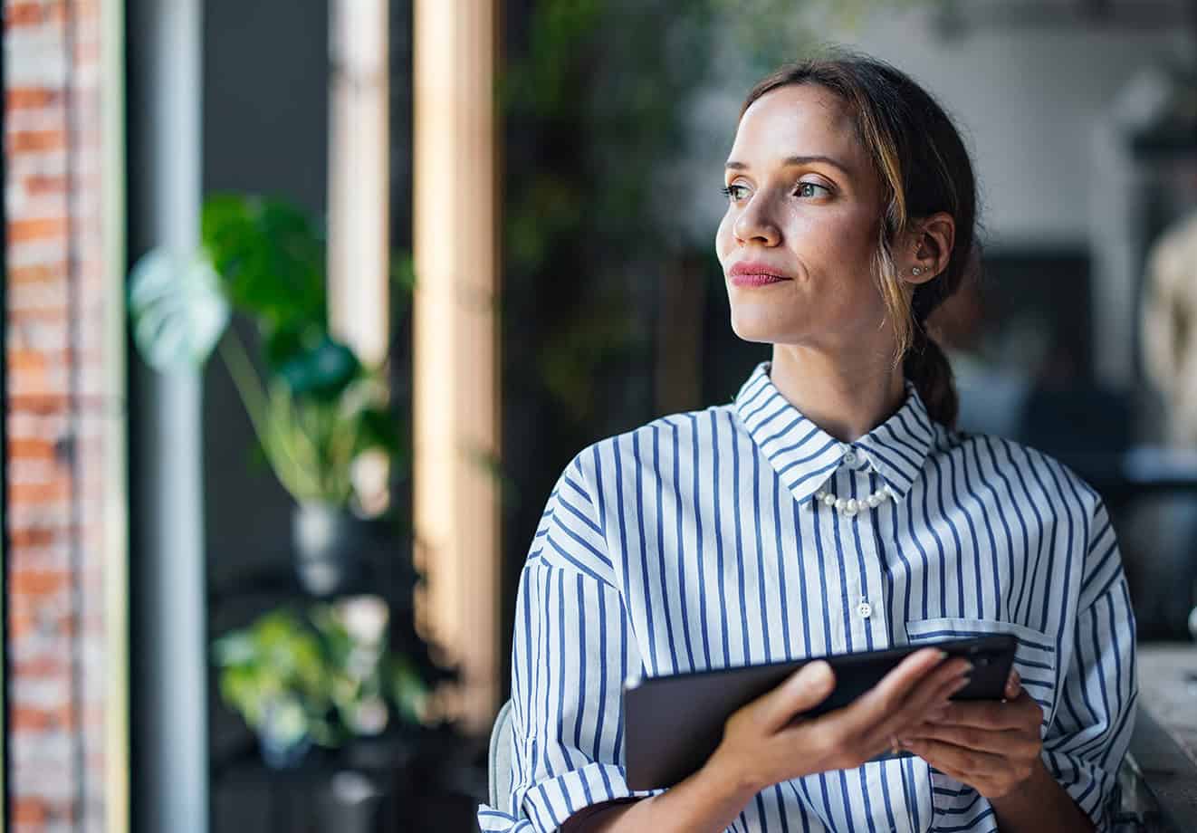 Teacher holding tablet looking thoughtfully out window