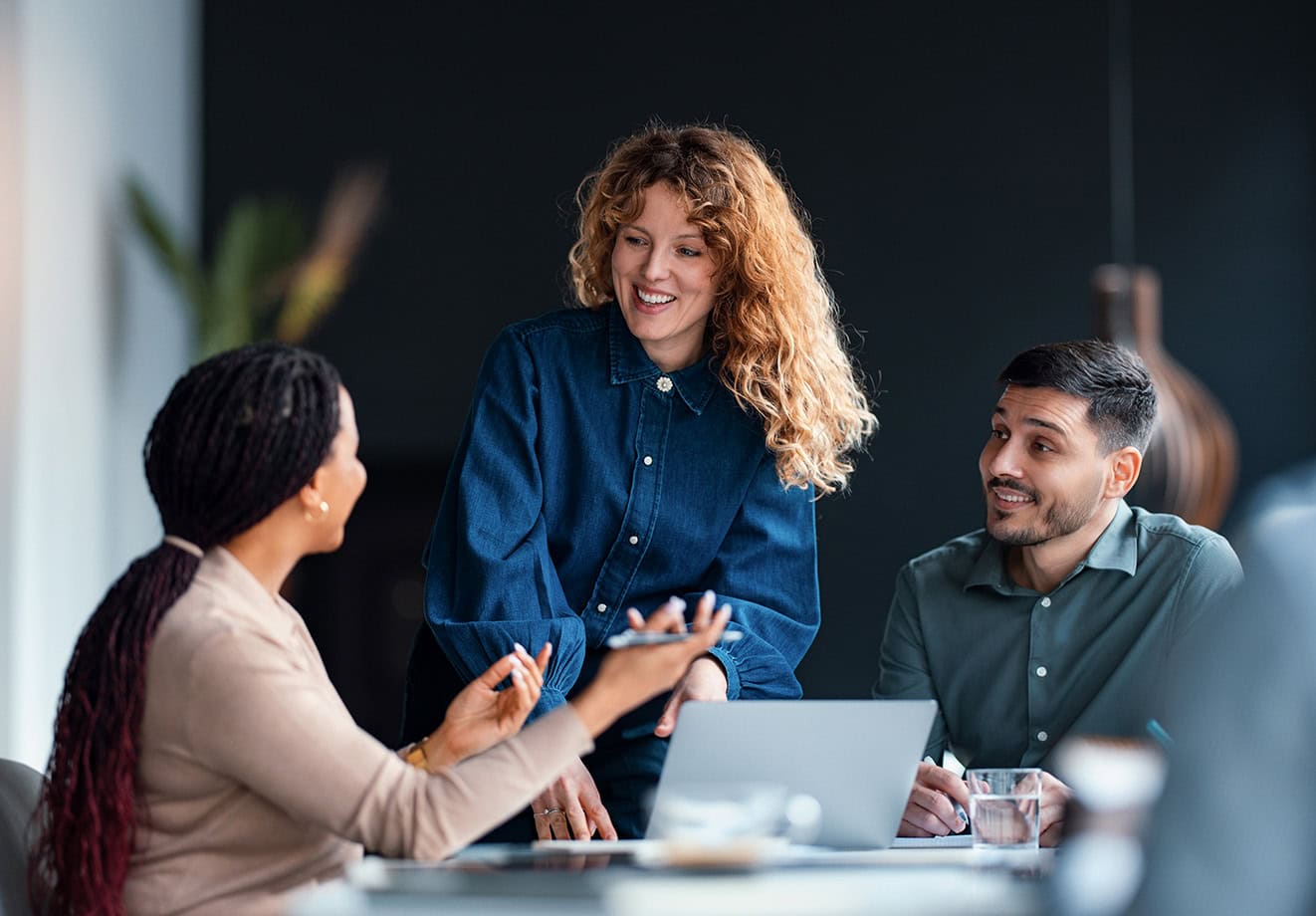 Three colleagues smiling and laughing at table.