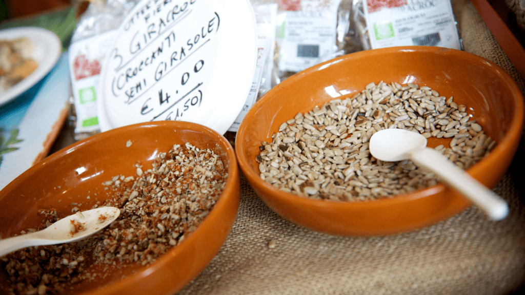 Ciotole con semi di girasole e cucchiai compostabili per assaggi durante una fiera agroalimentare.