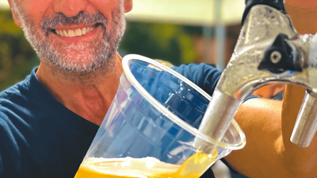 Bicchiere compostabile trasparente riempito di birra durante un evento.