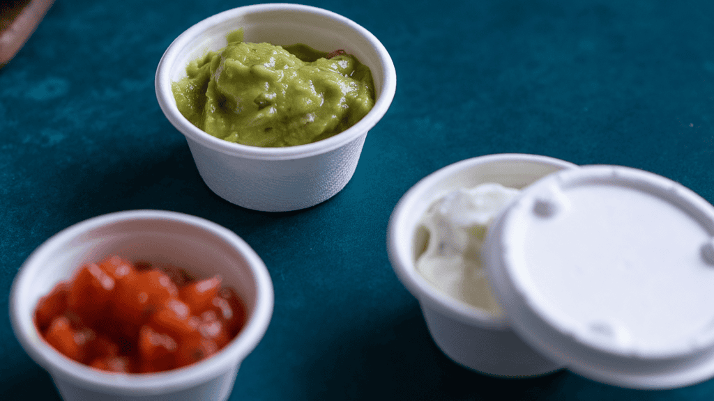 Contenitori compostabili con guacamole, salsa di pomodoro e panna acida, ideali per salse e assaggi.