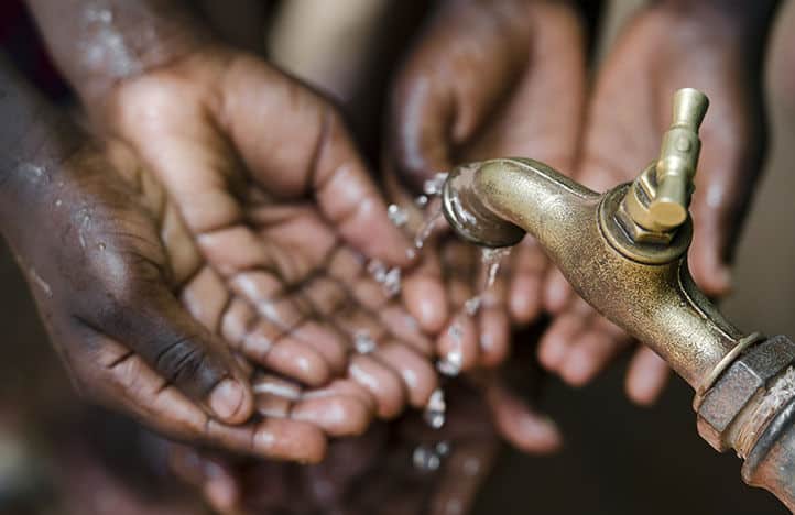 eau qui coule du robinet dans des mains de personnes noires