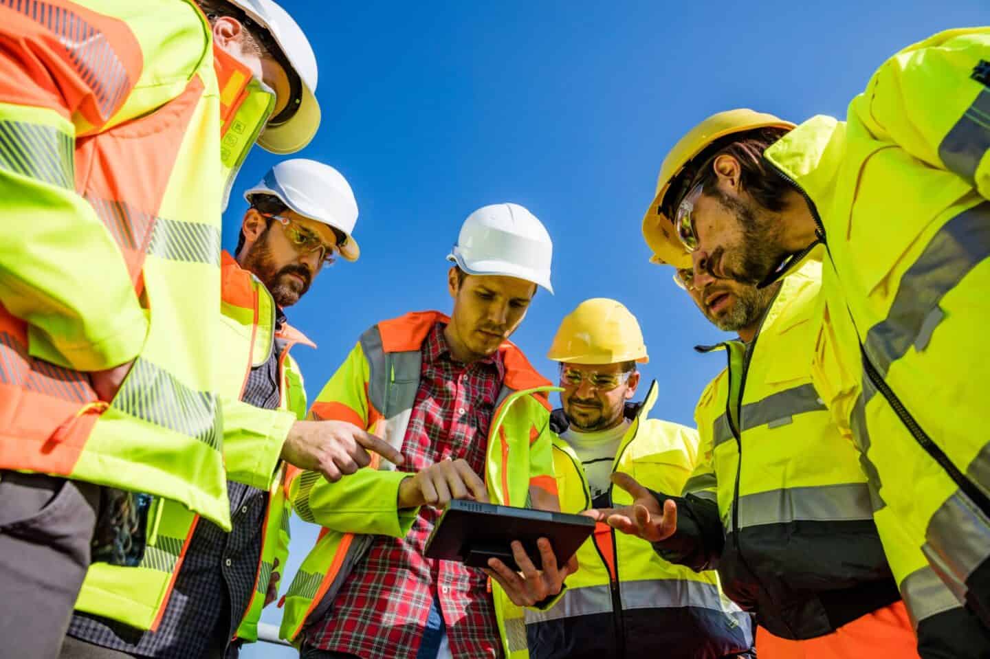 ouvriers rassemblés autour d'une tablette et ils discutent ensemble