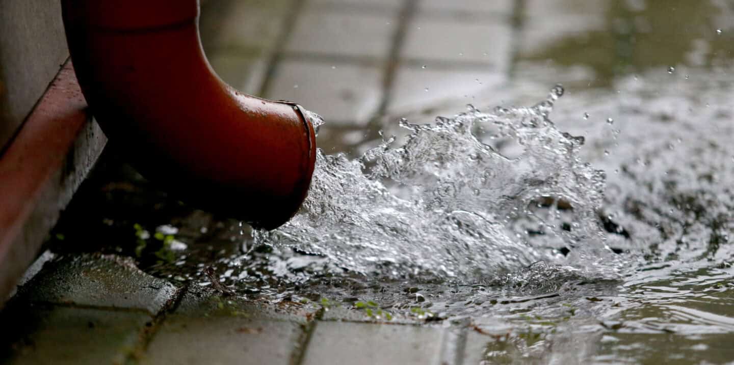 tuyau rouge rejetant de l'eau de pluie