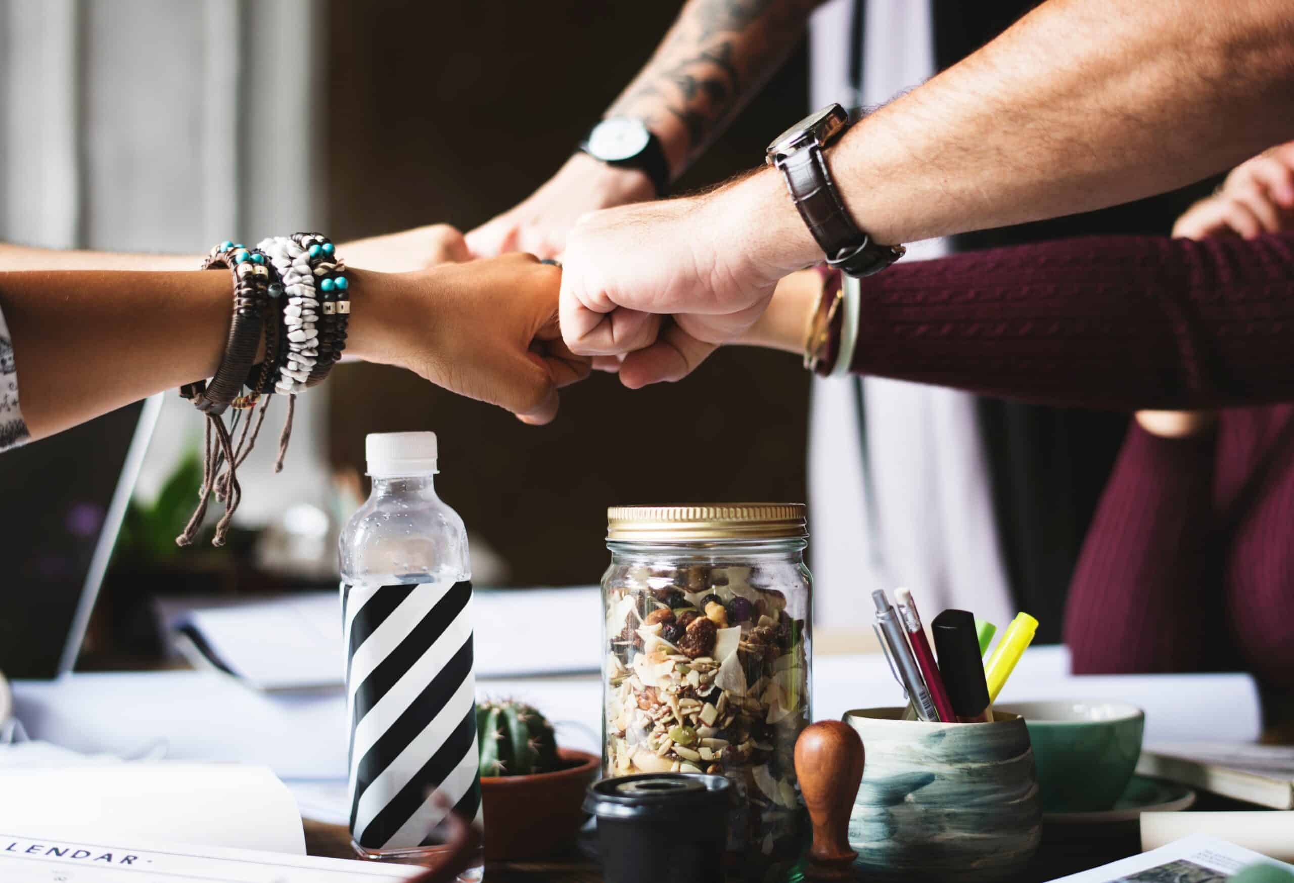 Fist bumps with 5 team members over a conference table.