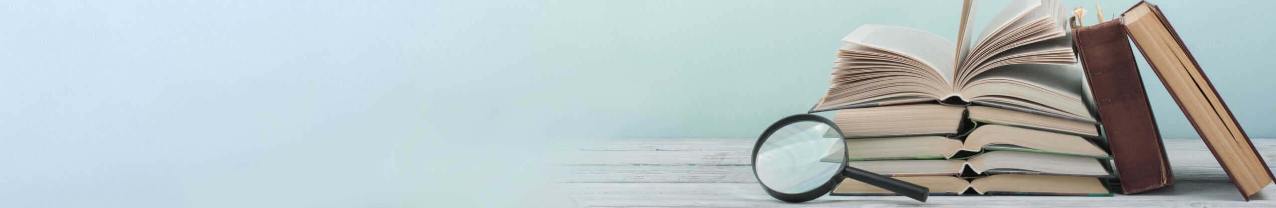 Pile of books with a magnifying glass.