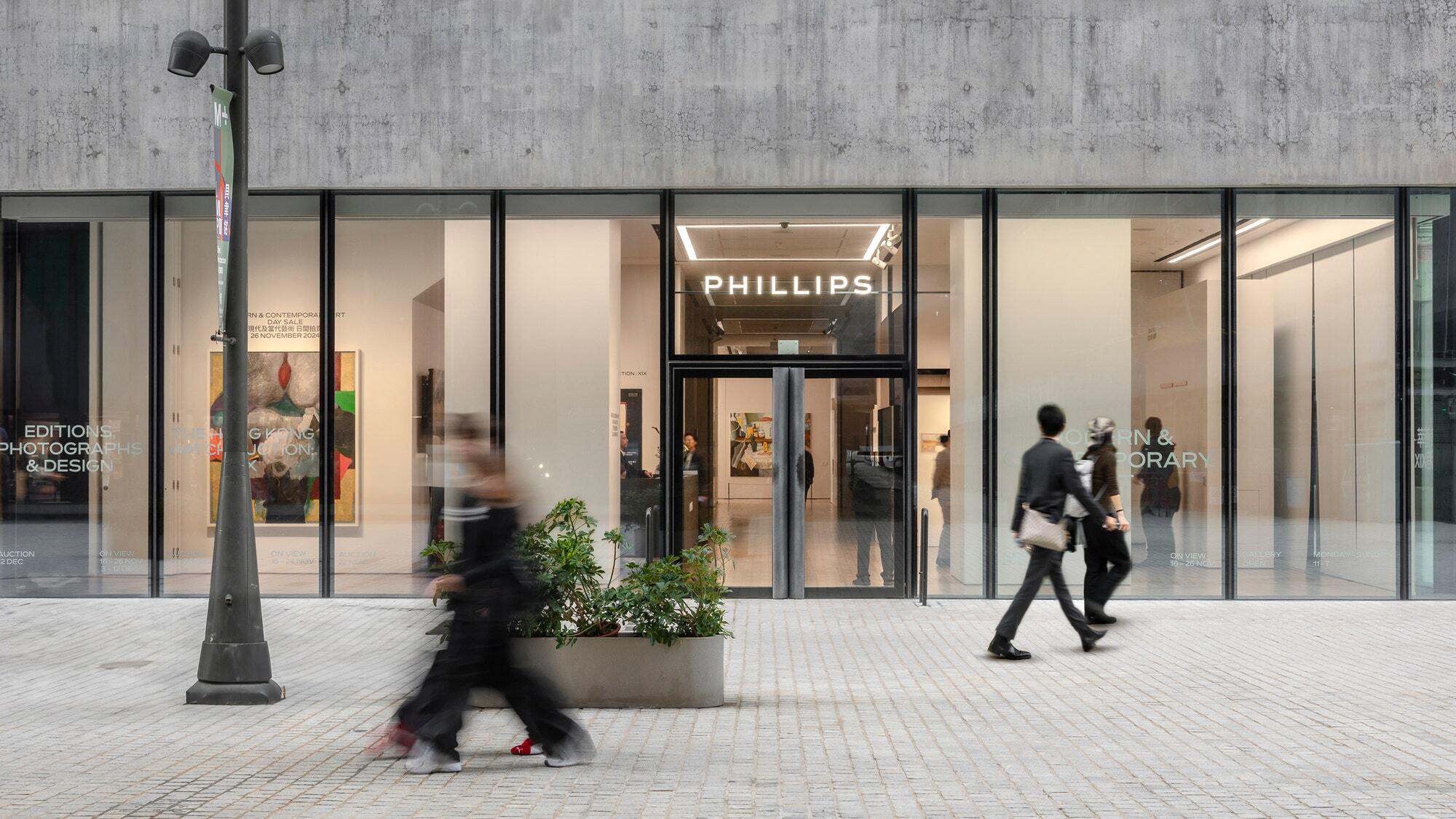 Exterior of the Phillips auction house gallery in Hong Kong, with pedestrians walking past the glass storefront