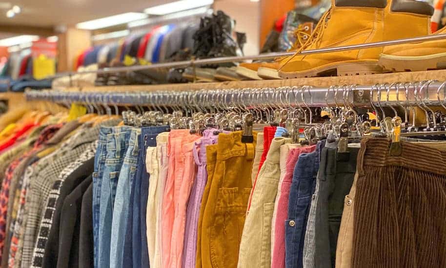 Different coloured trousers and shirts on the rack