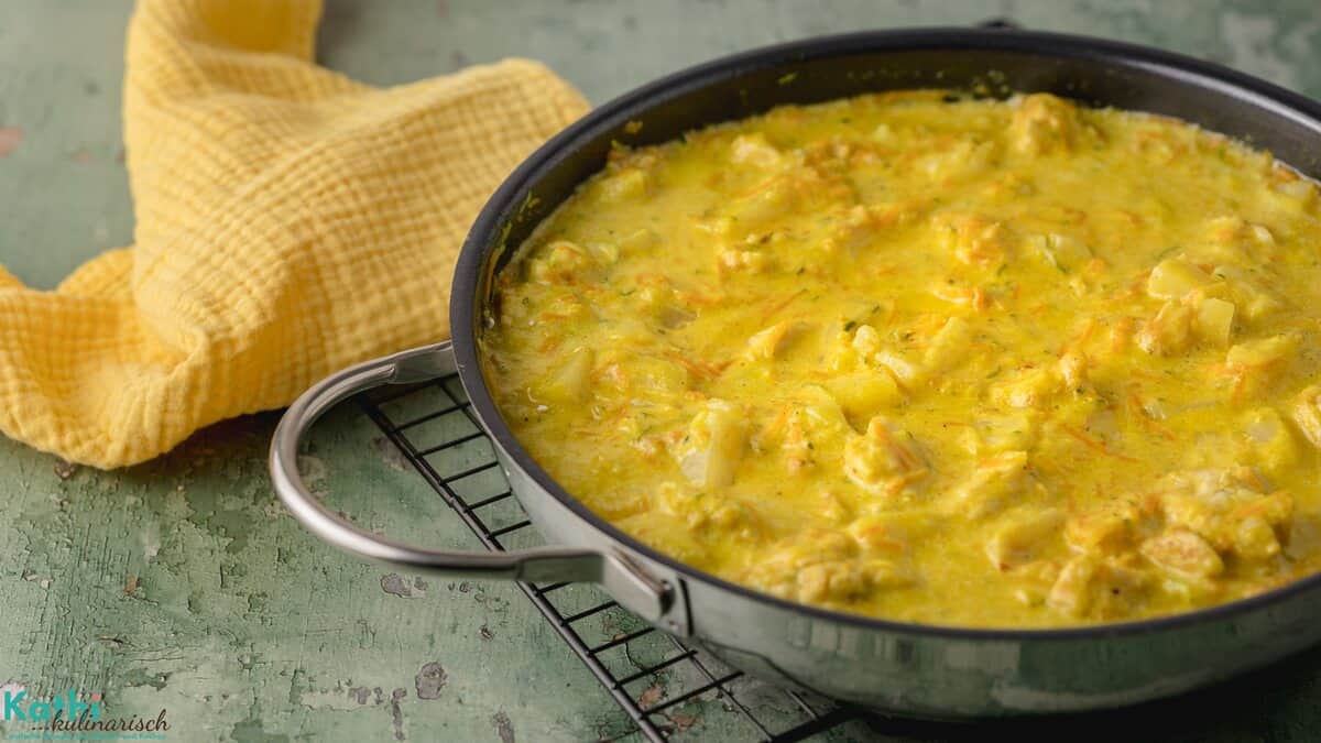 In einer Pfanne wurde ein Ananas Curry mit Hähnchen gekocht. Die cremige Textur ist sehr schön zu erkennen. Im Hintergrund liegt eine gelbe Serviette.