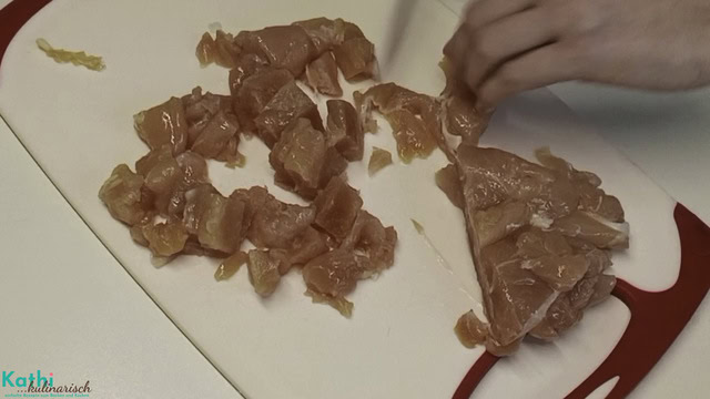 Hühnerfleisch wird in mundgerechte Stücke geschnitten.
