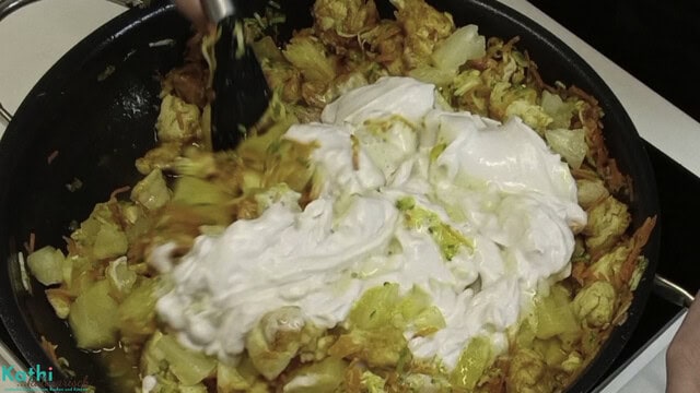 Kokosmilch wird zum Ananas Hähnchen Curry hinzugefügt.