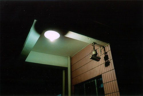 A dim lit entryway to a building with a CCTV camera.