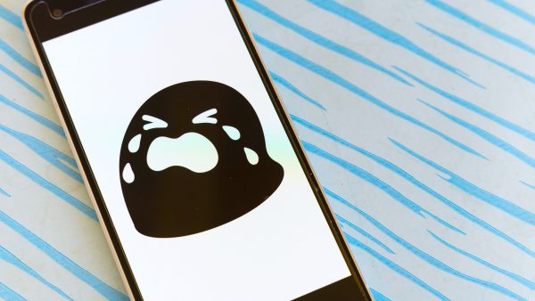 a smartphone, on a blue and white patterned surface, with a black and white crying emoji on the screen,