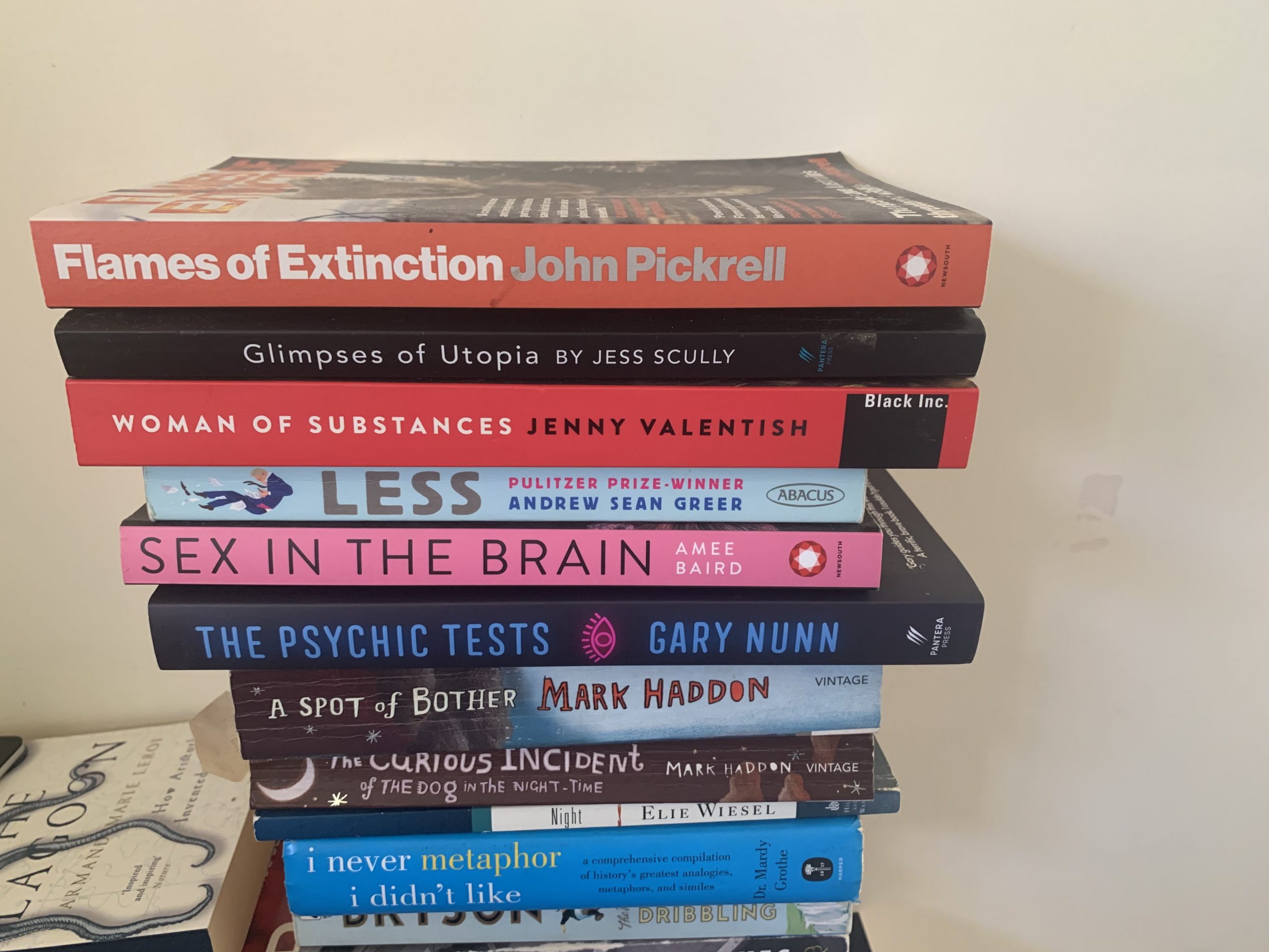 A stack of ten paperback books of various sizes