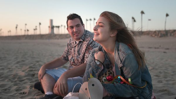 Left to right: David and Abbey on date, sitting together on the beach.