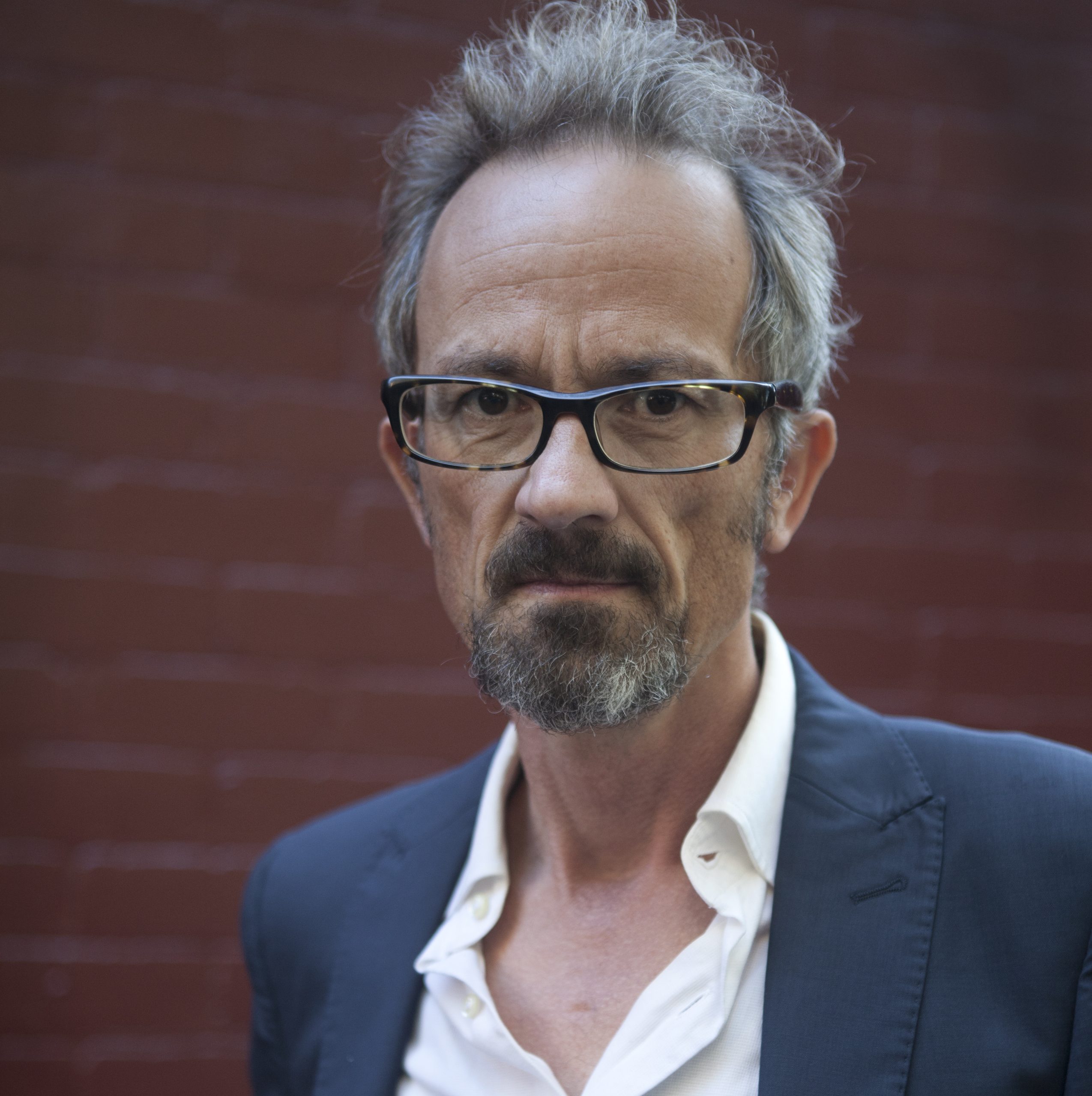The author Chris Womersley, wearing a white shirt, dark grey suit jacket and tortoise-shell glasses.