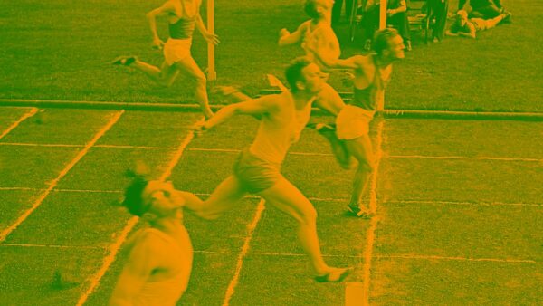 A vintage photograph of several men straining to cross the finish line in a running race.