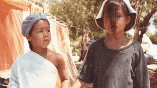 Two children stand holding hands.