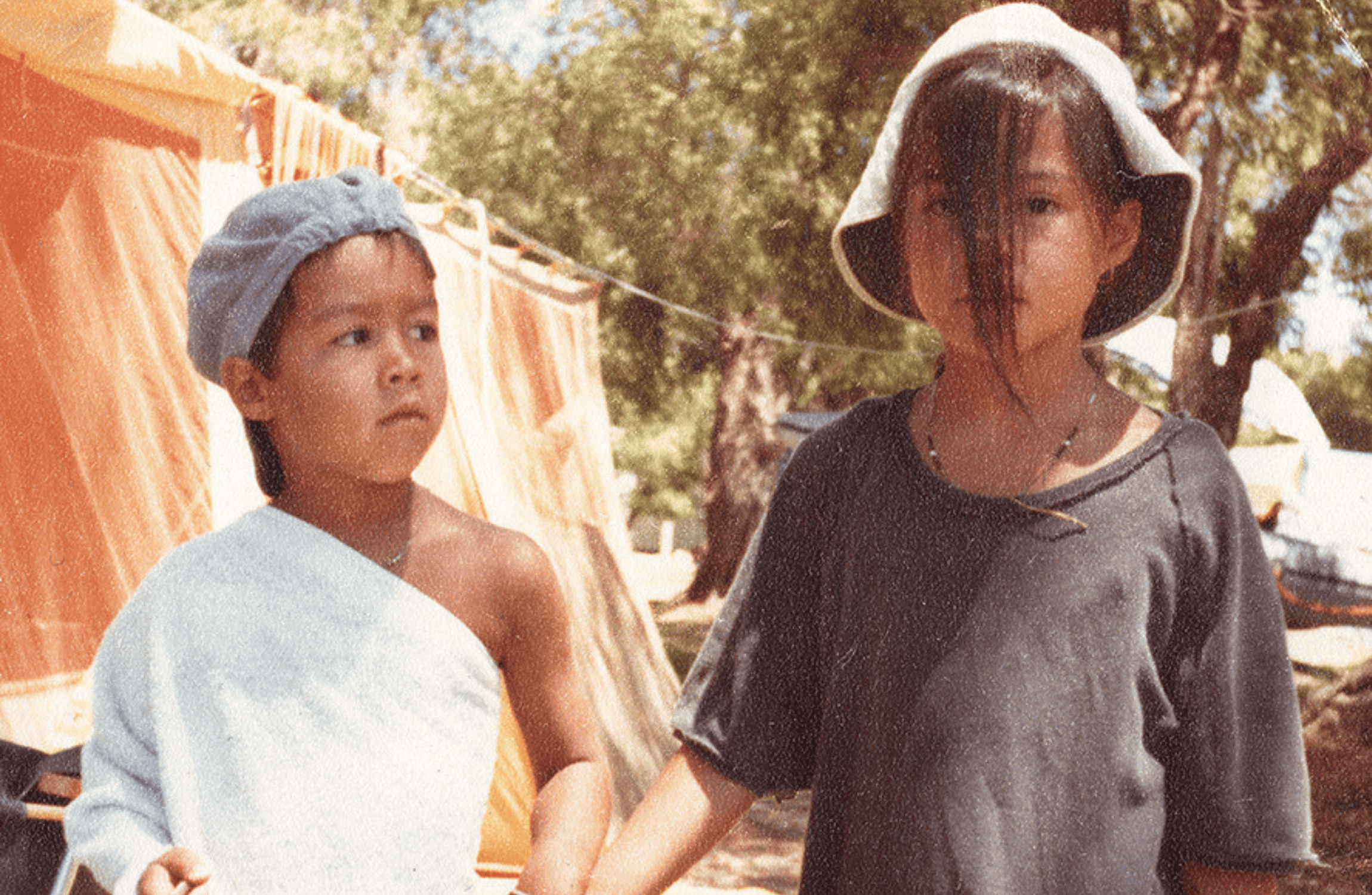 Two children stand holding hands.