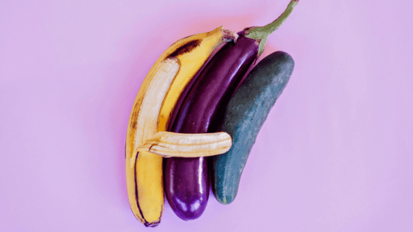 A banana hugging a long eggplant curled next to a small cucumber.