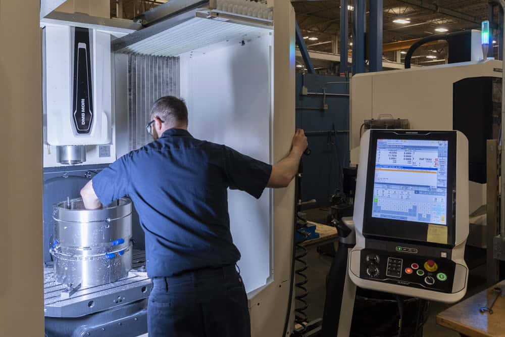 Team member Matt standing in the interior of a CMX 50 machine using his arm to make sure bearing is in place before machine starts